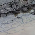 Asphalt driveway damage with cracking and water