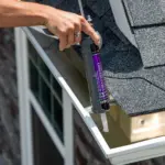 A LeafFilter installers applies caulking to seal clean, white gutters.