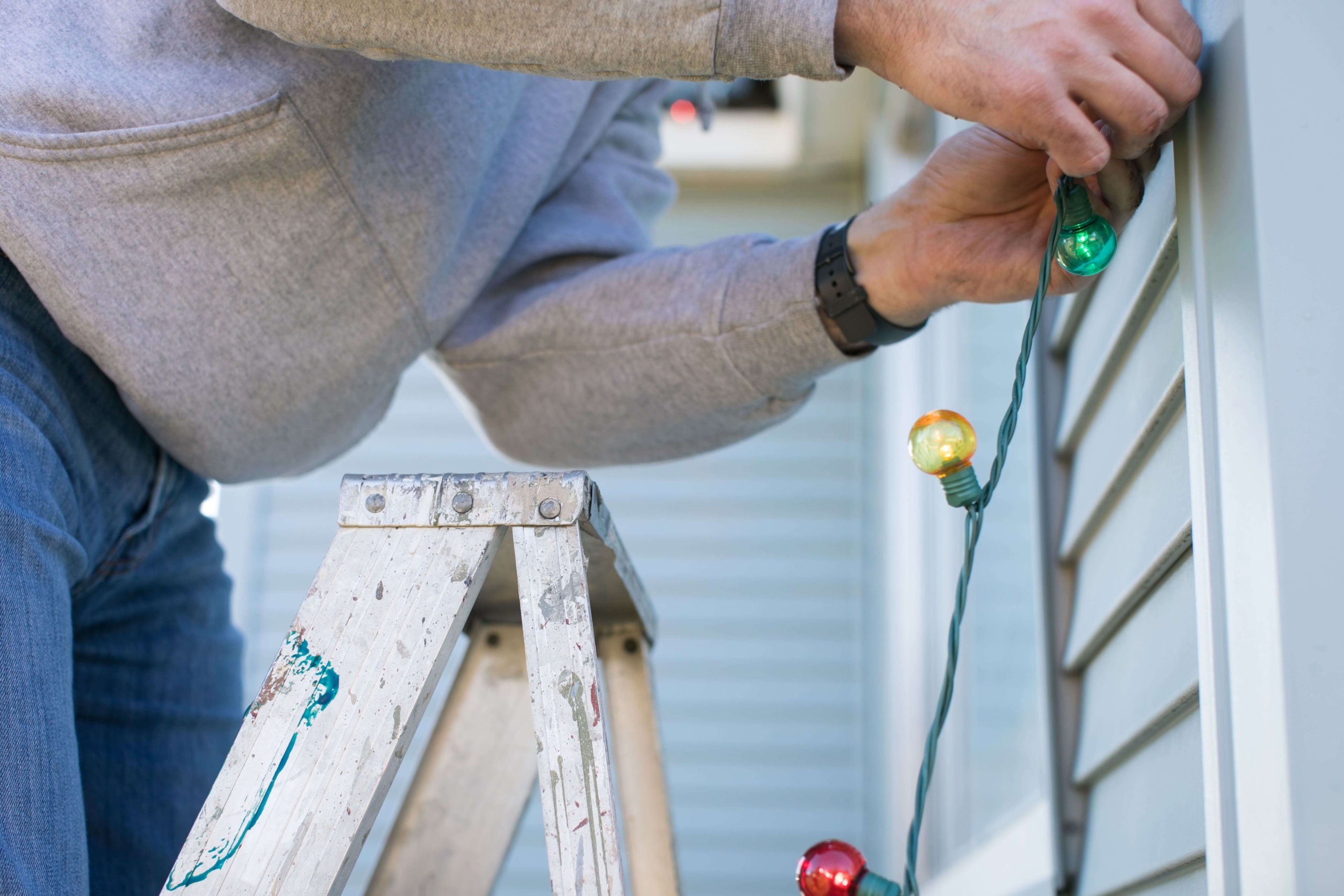 Hanging holiday lights by ladder