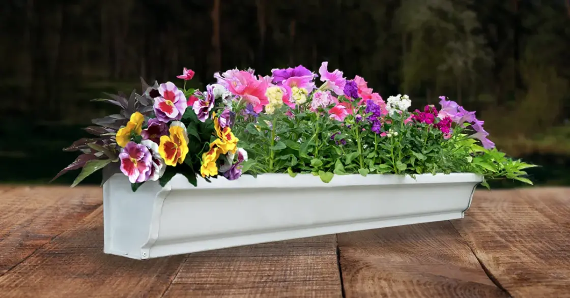 A gutter planter box filled with flowers and greenery