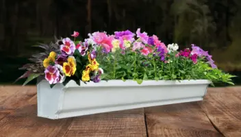 A gutter planter box filled with flowers and greenery