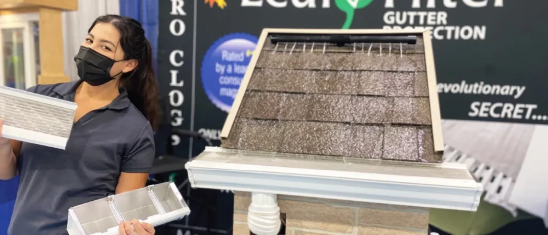 A masked LeafFilter event marketer shows off the gutter guards and demonstrates how they work