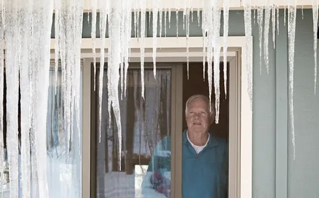 A homeowner looks at icicles with frustration