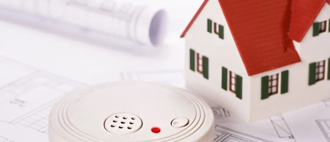 Smoke detector and small model home on top of home evacuation plans - home fire prevention and preparation