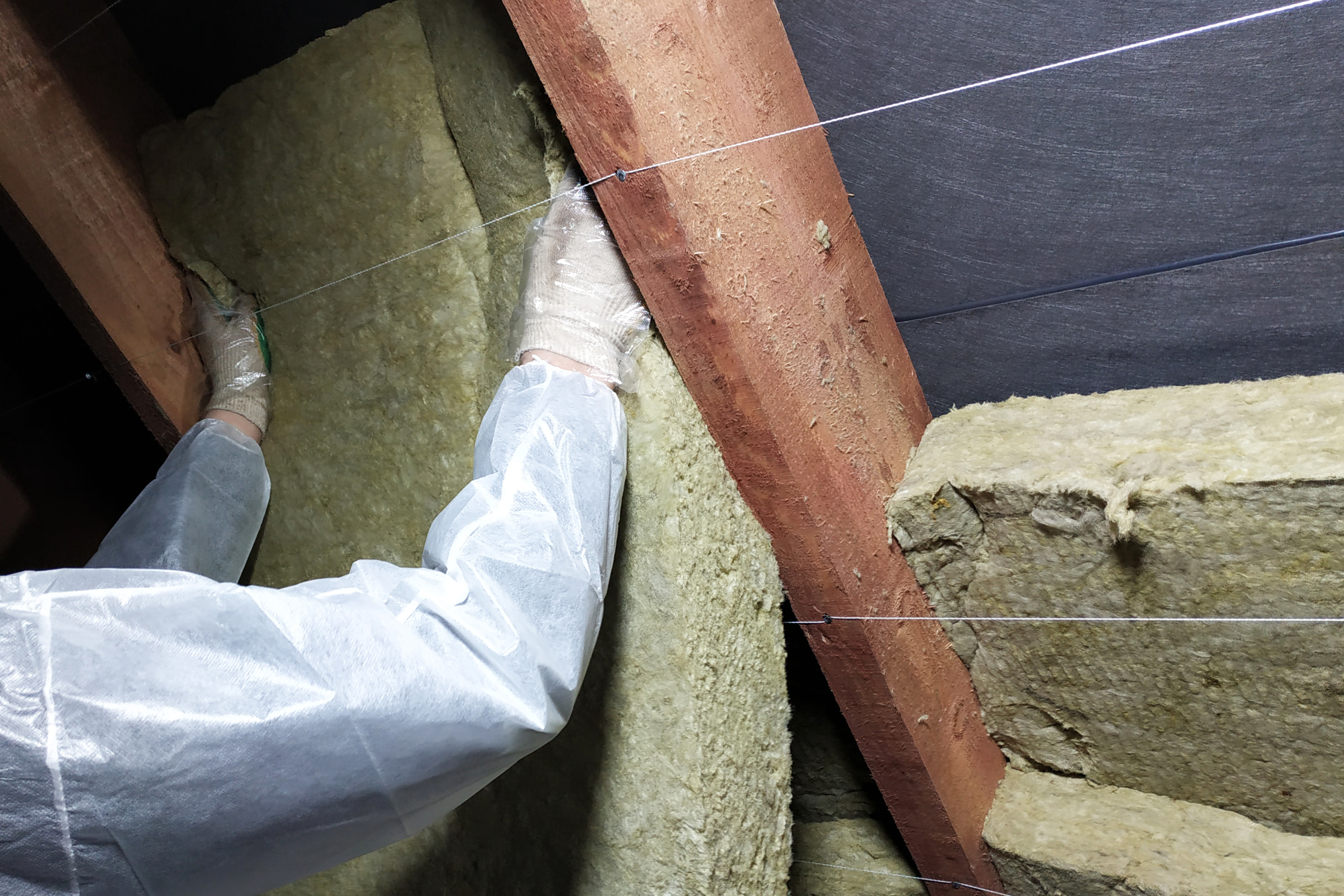 Man in protective gear installs new insulation in attic to winterize your home.