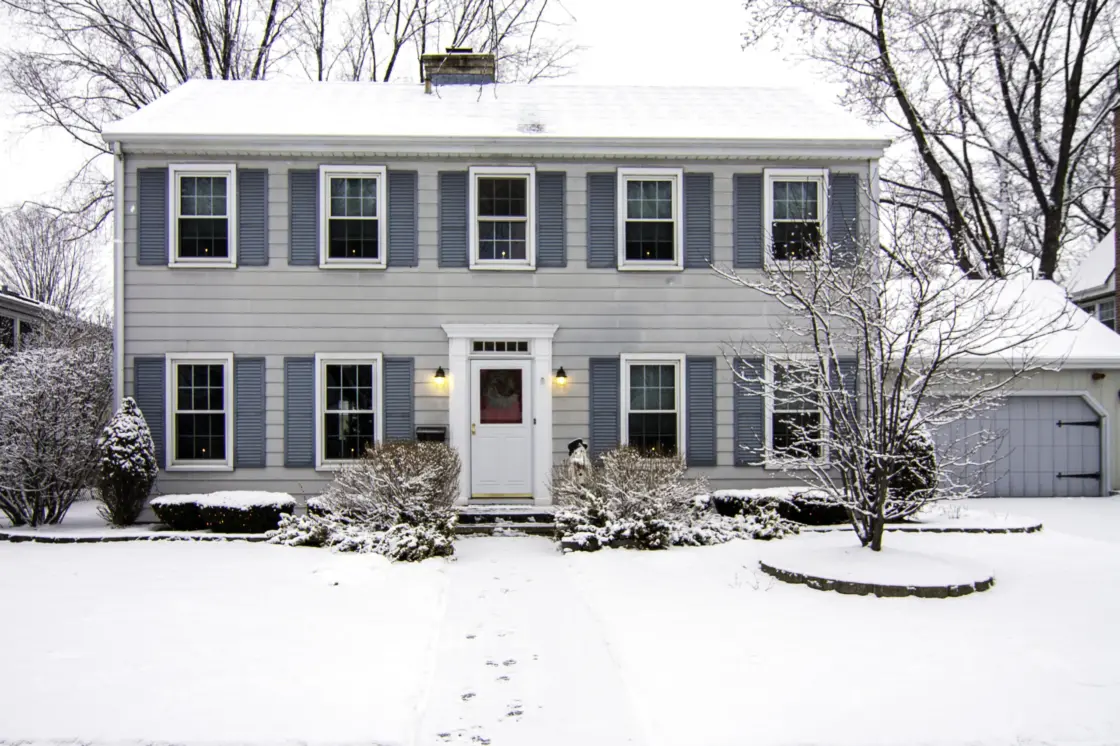 Exterior house snow on roof and lawn after winterize your home.