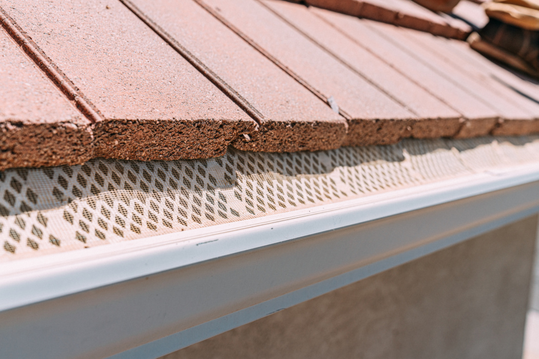 Close up of roof shingles and mesh screen gutter guards