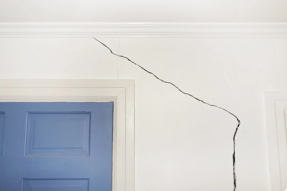 Crack in the wall around the door of a home, sign of foundation damage from water