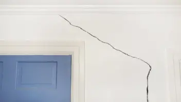 Crack in the wall around the door of a home, sign of foundation damage from water