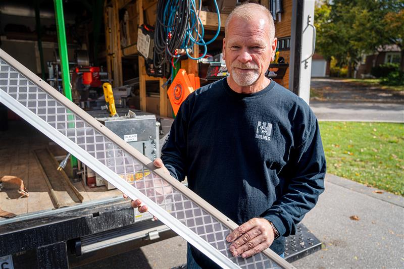 Mike Holmes holding LeafFilter gutter guard in front of work van to promote LeafFilter and Mike Holmes partnership