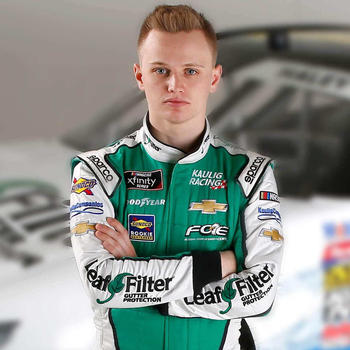 Justin Haley poses in LeafFilter-branded NASCAR gear before his race car