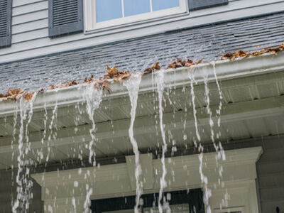 Gutters overflowing in a rain storm due to them being full of leaves